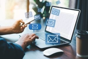 Person using a laptop with email notifications and smartphone, illustrating email marketing strategies and engagement for LeadNurtureClose®.