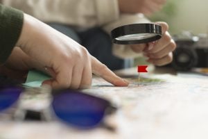 Hands pointing at a map with a magnifying glass and a red flag marker, illustrating geo-targeting strategies for local businesses in Elk Grove.